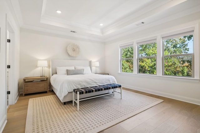 bedroom featuring a tray ceiling, ornamental molding, and light hardwood / wood-style floors