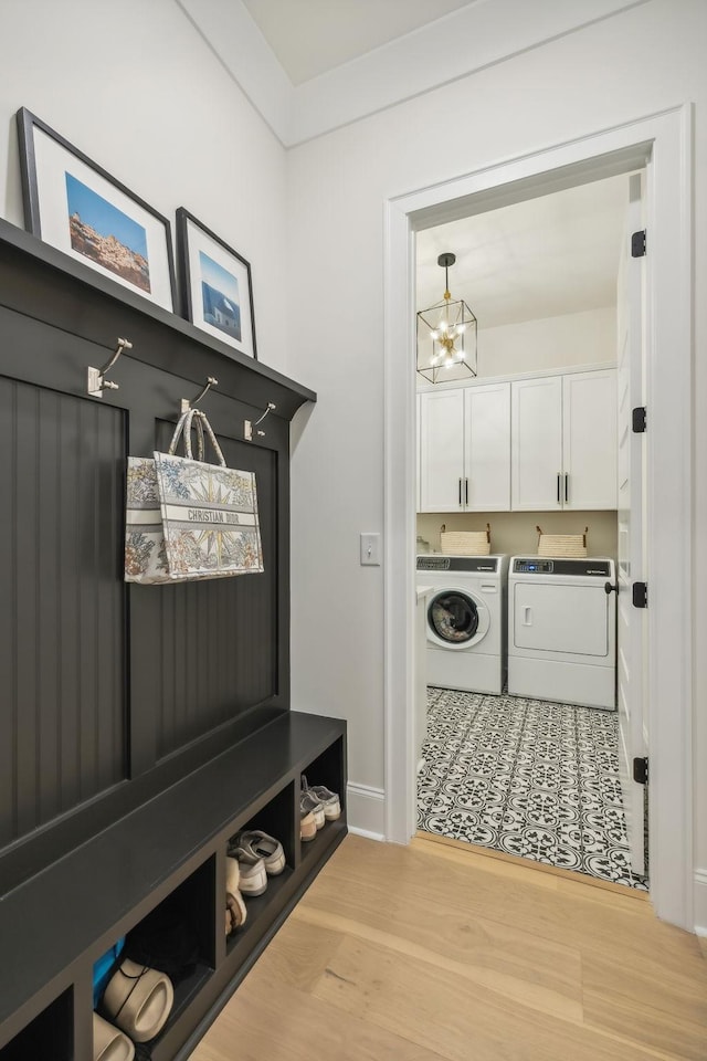 mudroom with an inviting chandelier, washing machine and dryer, and light wood-type flooring