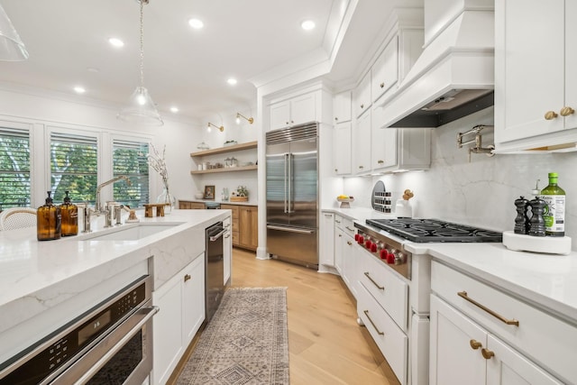 kitchen featuring stainless steel appliances, premium range hood, sink, and white cabinetry