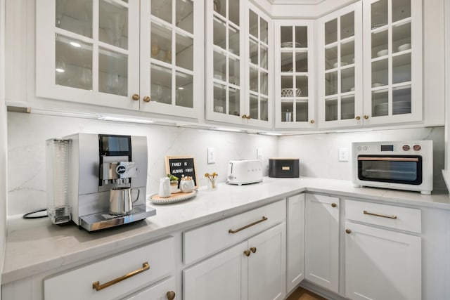 bar with light stone counters, tasteful backsplash, and white cabinets