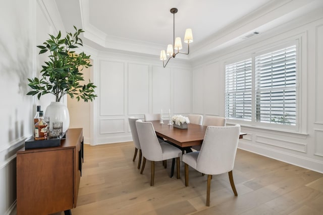 dining room with crown molding, a notable chandelier, and light hardwood / wood-style flooring