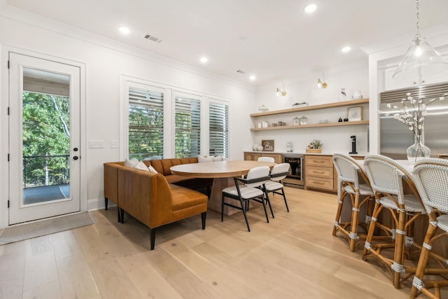 dining space with wine cooler, crown molding, and light hardwood / wood-style floors