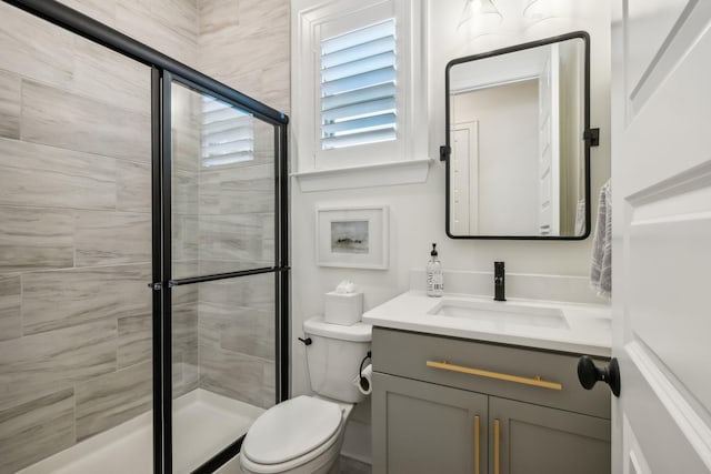 bathroom with vanity, a shower with shower door, and toilet