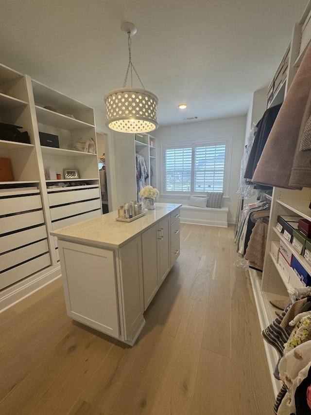 walk in closet with light hardwood / wood-style floors