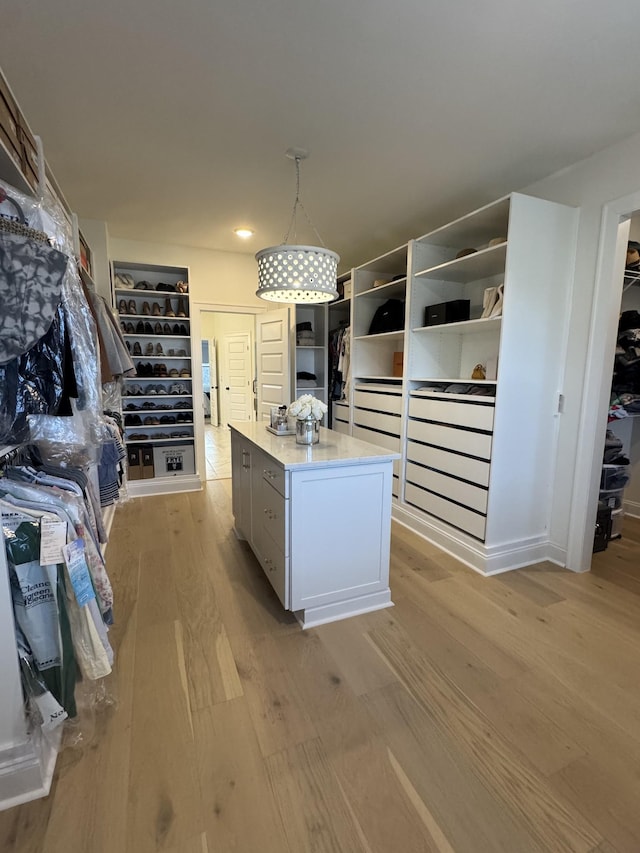 kitchen featuring light hardwood / wood-style floors, hanging light fixtures, a kitchen island, and white cabinets