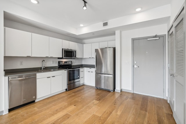 kitchen featuring light hardwood / wood-style floors, stainless steel appliances, track lighting, white cabinets, and sink