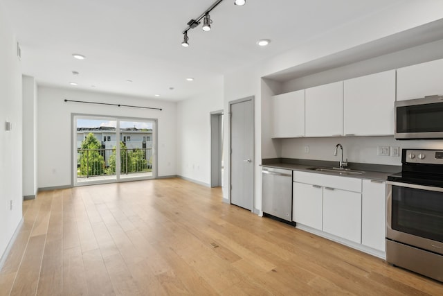 kitchen with white cabinets, stainless steel appliances, light hardwood / wood-style floors, sink, and rail lighting