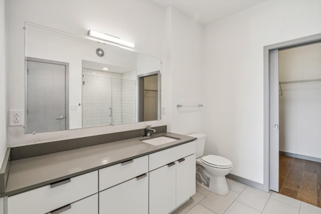 bathroom featuring a shower with shower door, vanity, tile patterned floors, and toilet