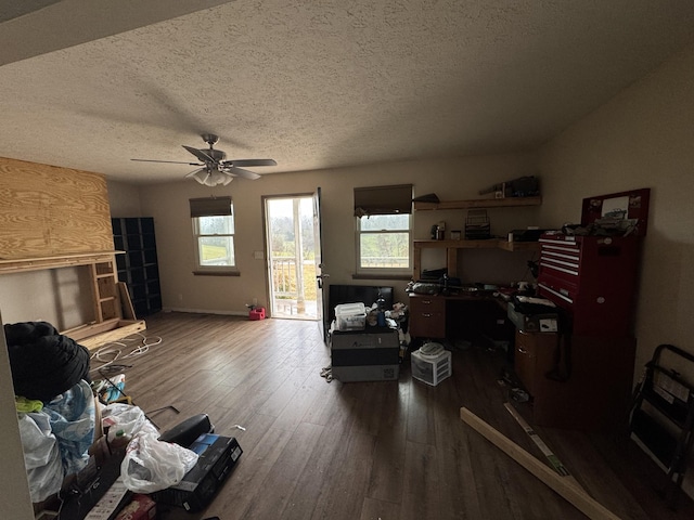 living room featuring ceiling fan, dark hardwood / wood-style floors, and a textured ceiling