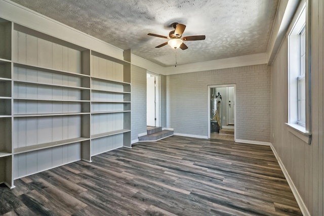 unfurnished living room featuring a textured ceiling, ceiling fan, brick wall, and dark hardwood / wood-style floors