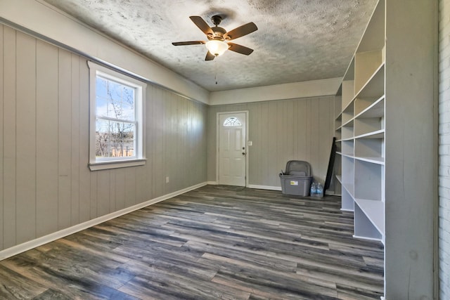 foyer featuring ceiling fan, dark hardwood / wood-style flooring, and wooden walls