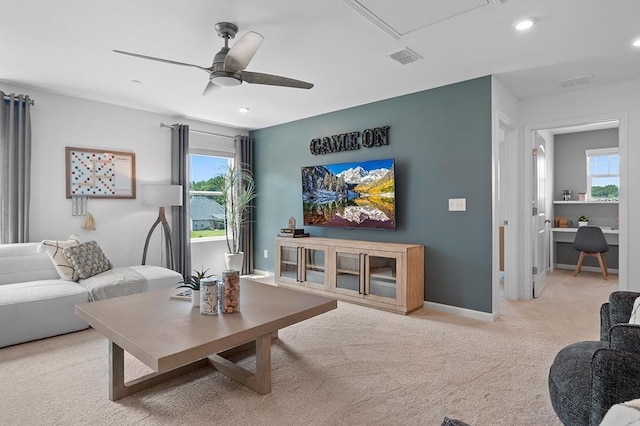 living room featuring ceiling fan, light carpet, and a wealth of natural light