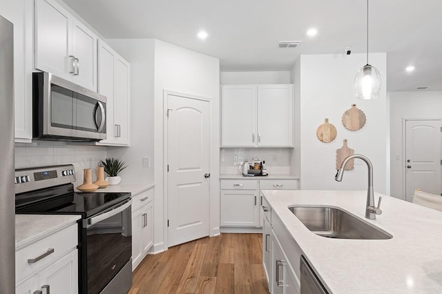 kitchen featuring appliances with stainless steel finishes, white cabinetry, tasteful backsplash, and sink