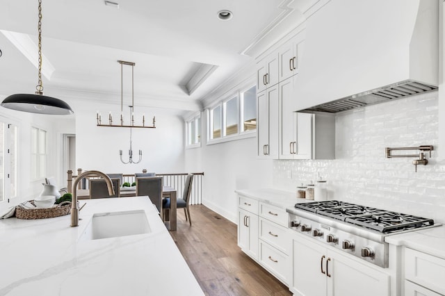 kitchen featuring sink, white cabinetry, stainless steel gas cooktop, light stone countertops, and custom range hood