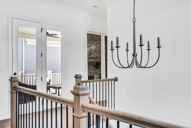 corridor featuring a healthy amount of sunlight, an inviting chandelier, crown molding, and hardwood / wood-style flooring