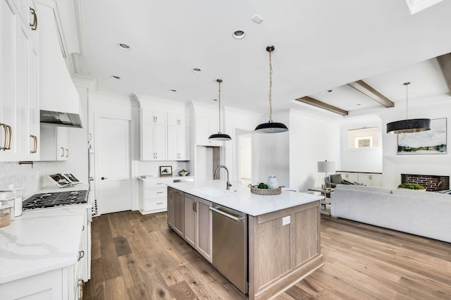 kitchen with decorative light fixtures, dishwasher, white cabinetry, and a center island with sink