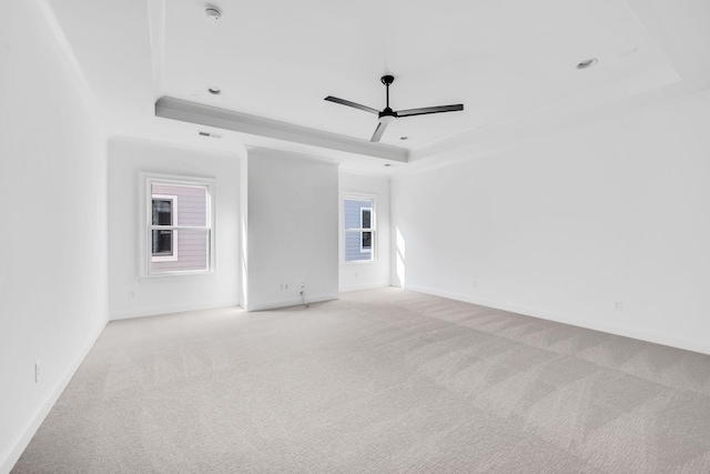 carpeted empty room with ceiling fan and a tray ceiling