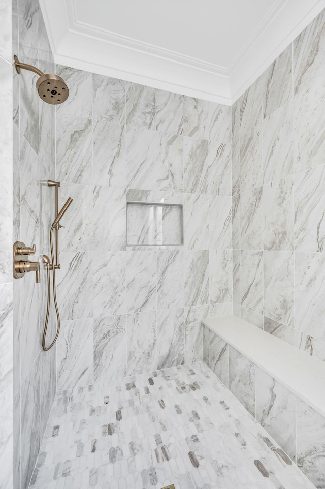 bathroom featuring crown molding and a tile shower