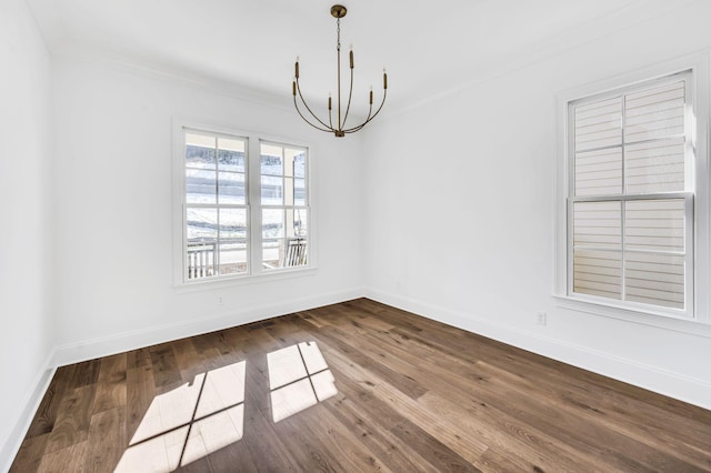 spare room with hardwood / wood-style floors, ornamental molding, and a chandelier