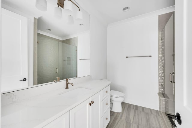 bathroom featuring toilet, vanity, a shower with door, and ornamental molding