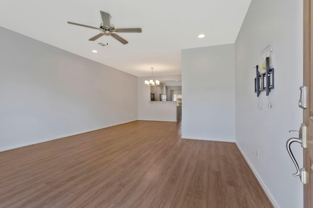 unfurnished living room featuring hardwood / wood-style flooring and ceiling fan with notable chandelier