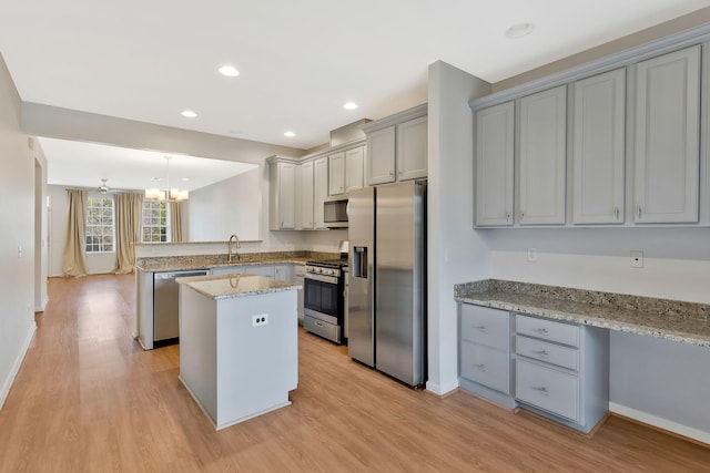 kitchen featuring ceiling fan, a kitchen island, decorative light fixtures, kitchen peninsula, and stainless steel appliances