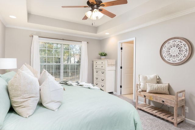 bedroom with ceiling fan, crown molding, light colored carpet, and a tray ceiling