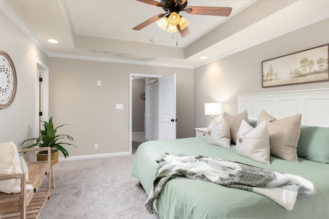 carpeted bedroom with ceiling fan, a tray ceiling, and crown molding