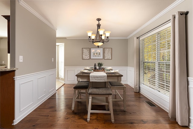 dining area with dark wood-type flooring, crown molding, and a chandelier