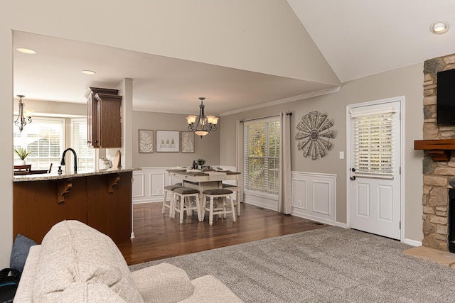 dining space with dark carpet, a notable chandelier, lofted ceiling, a fireplace, and crown molding