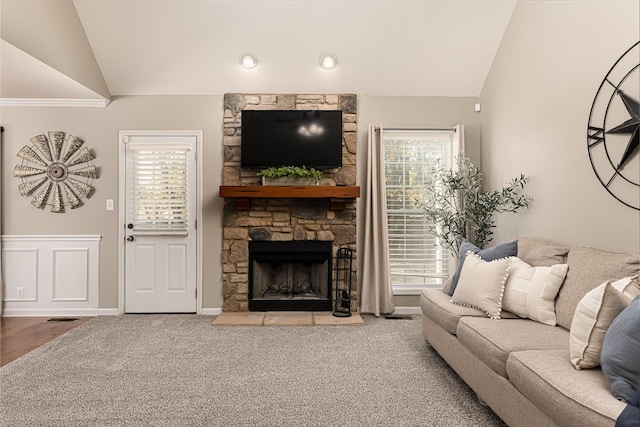 carpeted living room with lofted ceiling and a stone fireplace