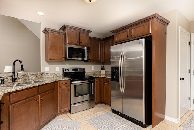 kitchen featuring stainless steel appliances, sink, kitchen peninsula, light stone counters, and light tile patterned floors