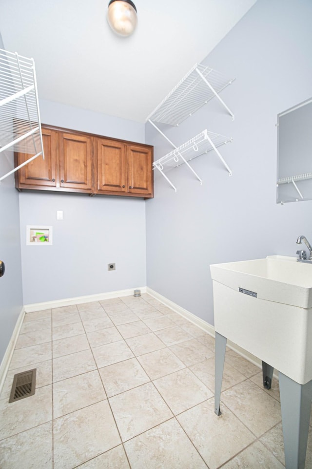 clothes washing area with light tile patterned floors, hookup for a washing machine, visible vents, baseboards, and cabinet space