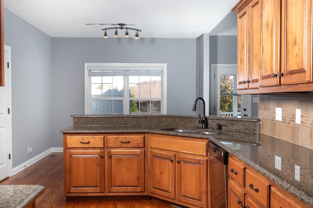 kitchen with a wealth of natural light, brown cabinets, a sink, and dishwasher