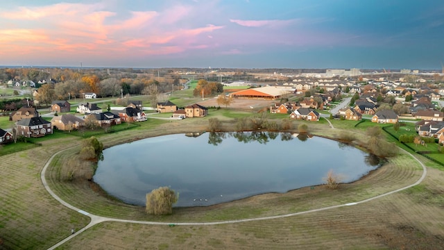 aerial view at dusk with a water view and a residential view