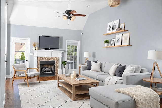 living area with light wood-style floors, a wealth of natural light, ceiling fan, and a tiled fireplace