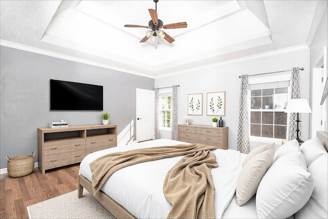 bedroom featuring ceiling fan, a tray ceiling, wood finished floors, and ornamental molding