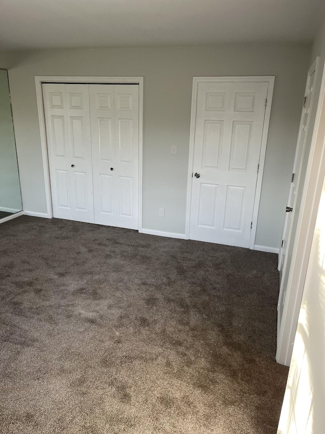 unfurnished bedroom with a closet and dark carpet