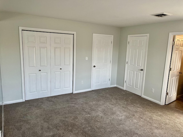 unfurnished bedroom with dark colored carpet and two closets