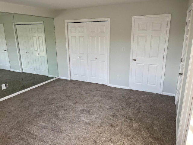 unfurnished bedroom with dark carpet and multiple closets