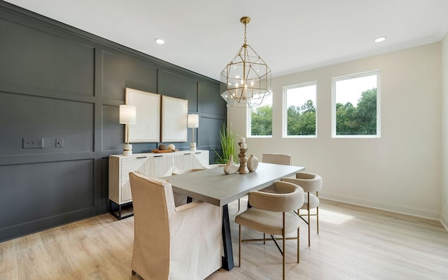 dining room with an inviting chandelier, ornamental molding, and light wood-type flooring