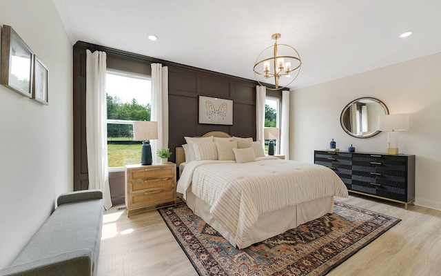 bedroom featuring light wood-type flooring, a notable chandelier, and multiple windows