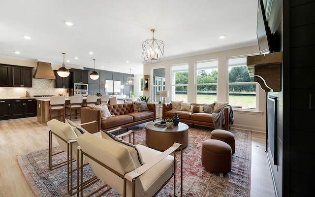 living room with light hardwood / wood-style floors and a notable chandelier