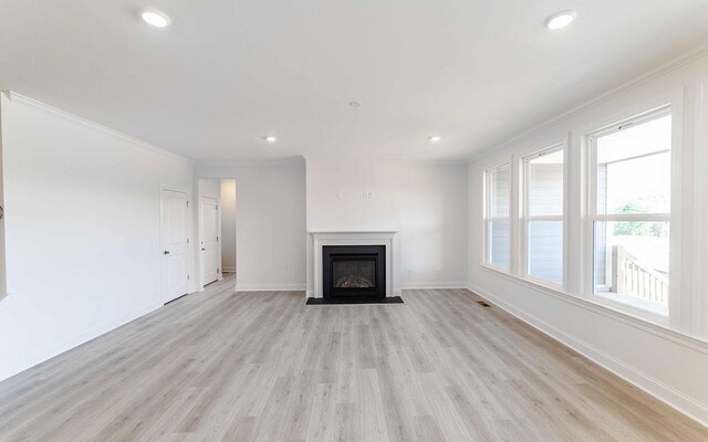 7934 Pine St, Fairview, TN 37062 - unfurnished living room with light wood-type flooring, crown molding, a fireplace with flush hearth, baseboards, and recessed lighting