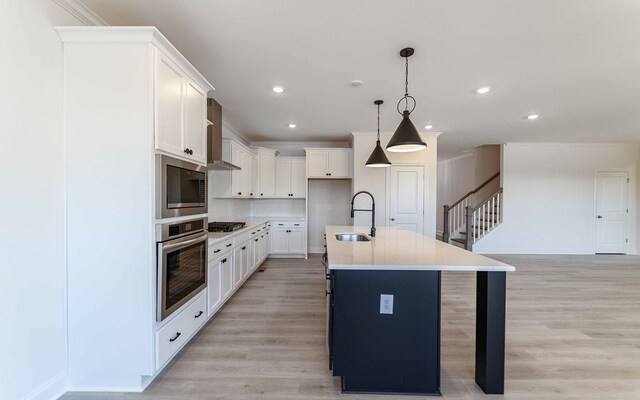 7934 Pine St, Fairview, TN 37062 - kitchen with stainless steel appliances, a sink, wall chimney exhaust hood, a kitchen island with sink, and white cabinets