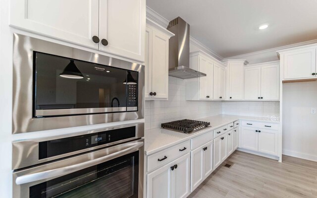 7934 Pine St, Fairview, TN 37062 - kitchen featuring appliances with stainless steel finishes, wall chimney range hood, light countertops, white cabinets, and tasteful backsplash
