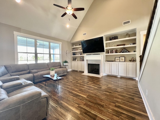 living room featuring high vaulted ceiling, built in shelves, ceiling fan, and dark wood-type flooring