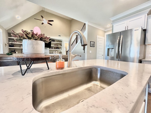 kitchen featuring stainless steel refrigerator with ice dispenser, white cabinetry, sink, ornamental molding, and light stone counters