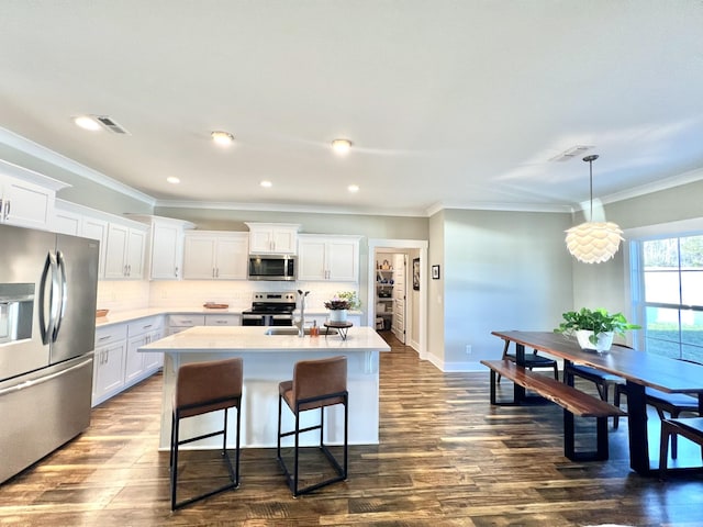 kitchen with appliances with stainless steel finishes, tasteful backsplash, a kitchen island with sink, dark wood-type flooring, and white cabinets