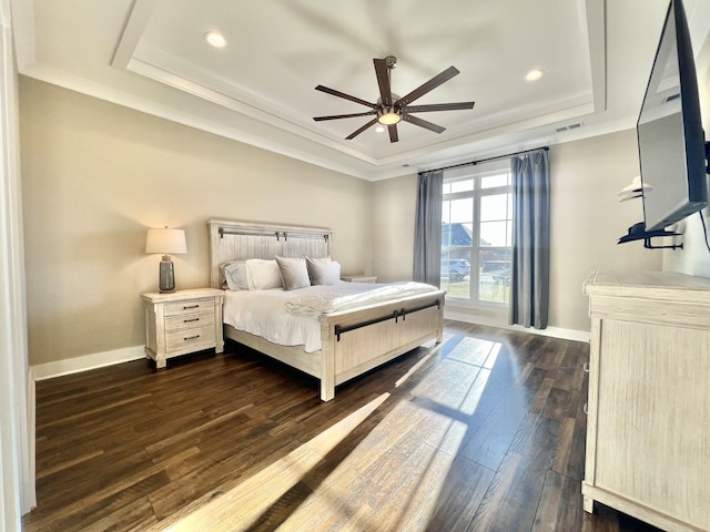 bedroom with ceiling fan, dark hardwood / wood-style flooring, ornamental molding, and a tray ceiling